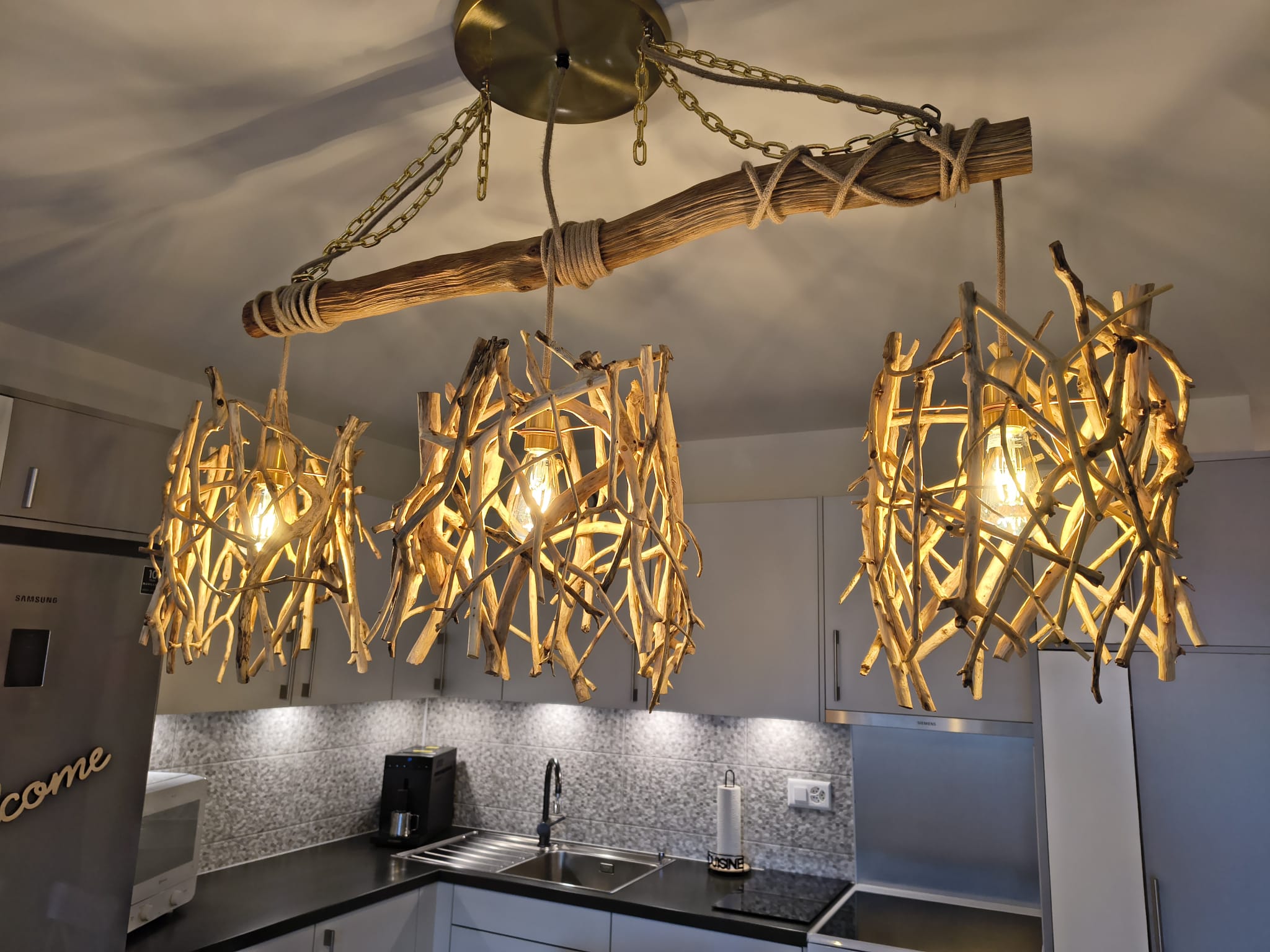 Chandelier suspendu à trois abat-jours de branches de bois flotté au-dessus d'un îlot de cuisine