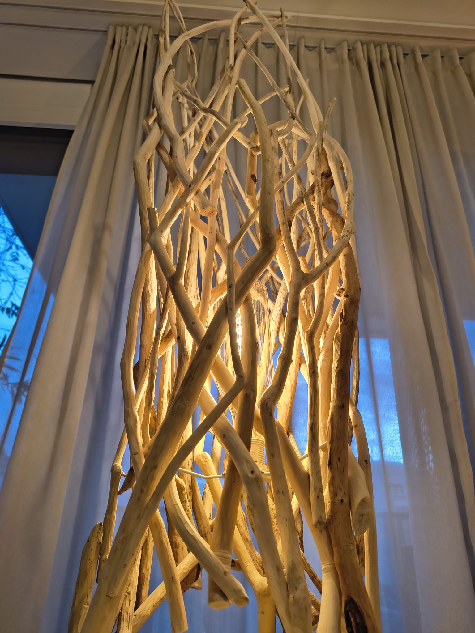 Détail du sommet de la lampe conique, bâtons de bois flotté entrecroisés autour de l'ampoule